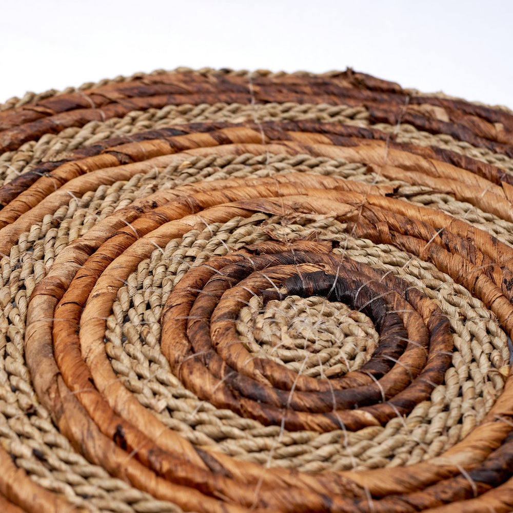 Close-up of a woven mat with concentric circles in brown and beige tones.