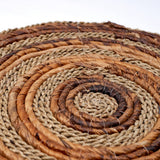 Close-up of a woven mat with concentric circles in brown and beige tones.