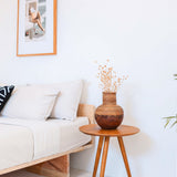Wicker vase on a wooden side table in a living room setting.