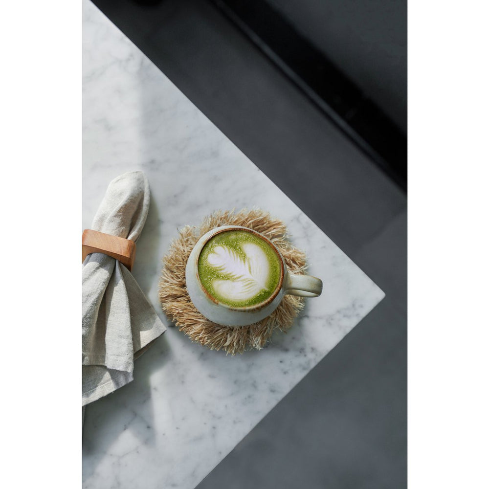 Cup of green tea with latte art on a marble surface
