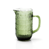 Green glass pitcher with ribbed texture on a white background