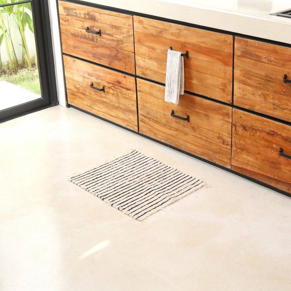 Wooden kitchen cabinets with a towel hanging on a rack, floor vent in the foreground.