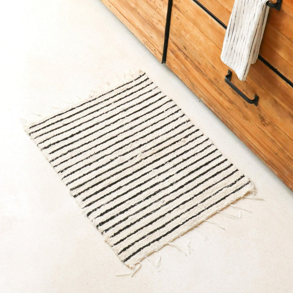 Striped rug on a light-colored floor next to a wooden cabinet.