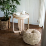 Woven side table and ottoman with a plant in a room.