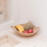Fruit bowl with bananas, apples, and a melon on a kitchen counter.