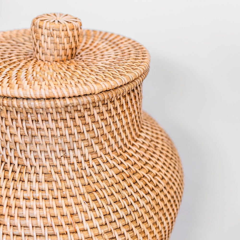 Woven rattan jar with a lid on a light gray background