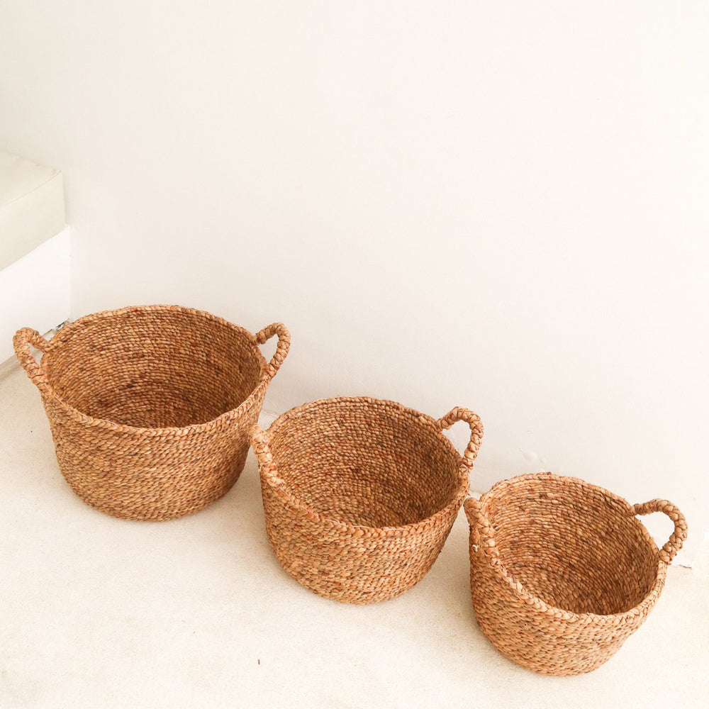 Three woven baskets of different sizes on a white surface
