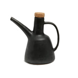 Black ceramic oil dispenser with a cork lid on a white background