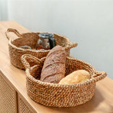 Woven baskets with bread and a bottle on a wooden surface