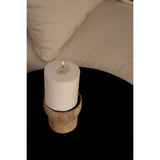 White candle on a wooden coaster with a blurred background