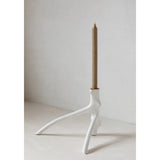 White candle holder with a beige candle on a light gray background