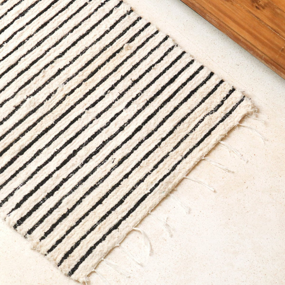 Beige rug with black stripes on a wooden floor