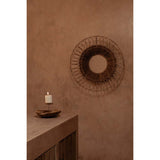Decorative wall mirror with a candle on a wooden surface against a brown wall.