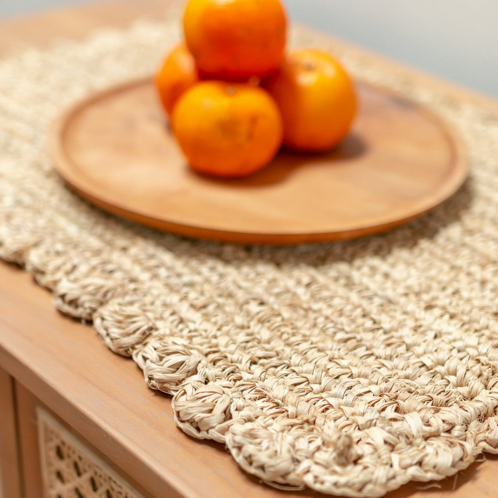 Wooden plate with oranges on a textured woven mat