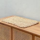 Woven mat on a wooden surface with a neutral background