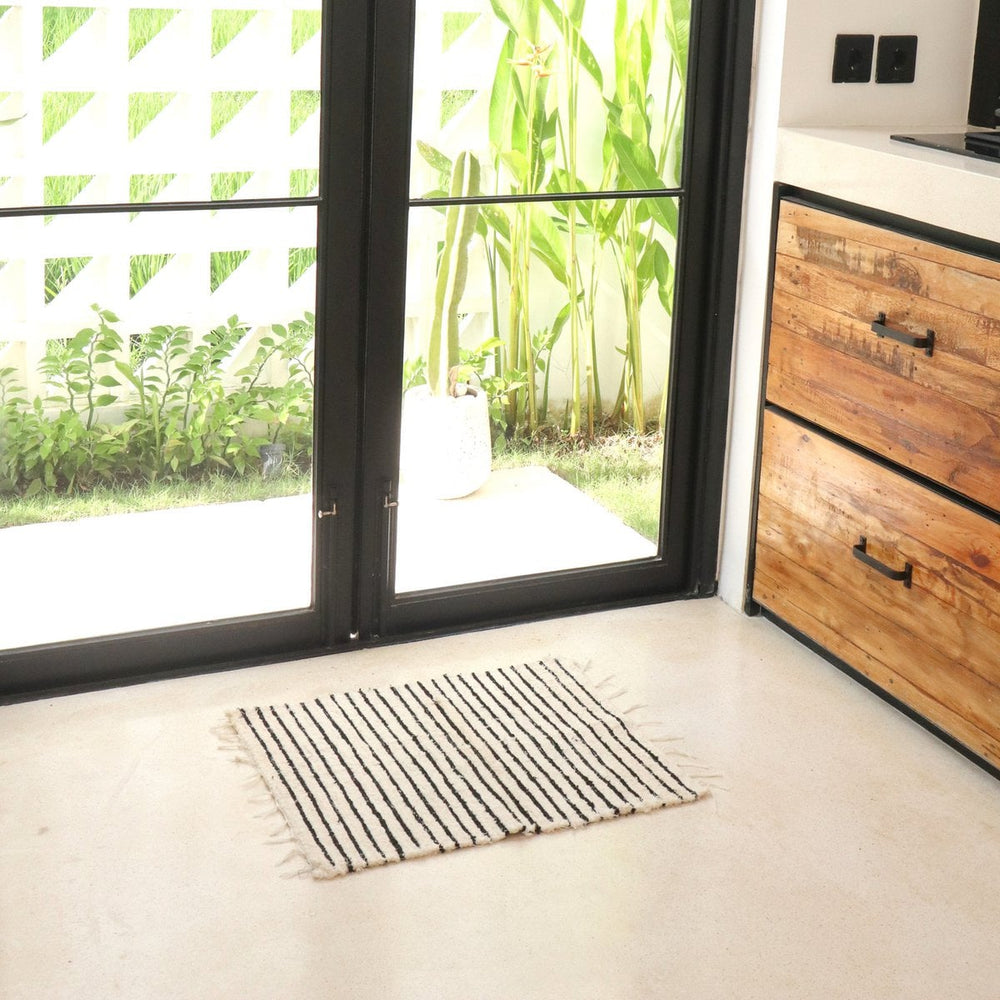 Striped rug on a light-colored floor with a wooden cabinet and glass doors in the background.
