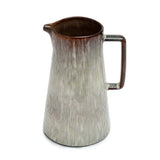 Ceramic pitcher with textured surface and brown rim on a white background