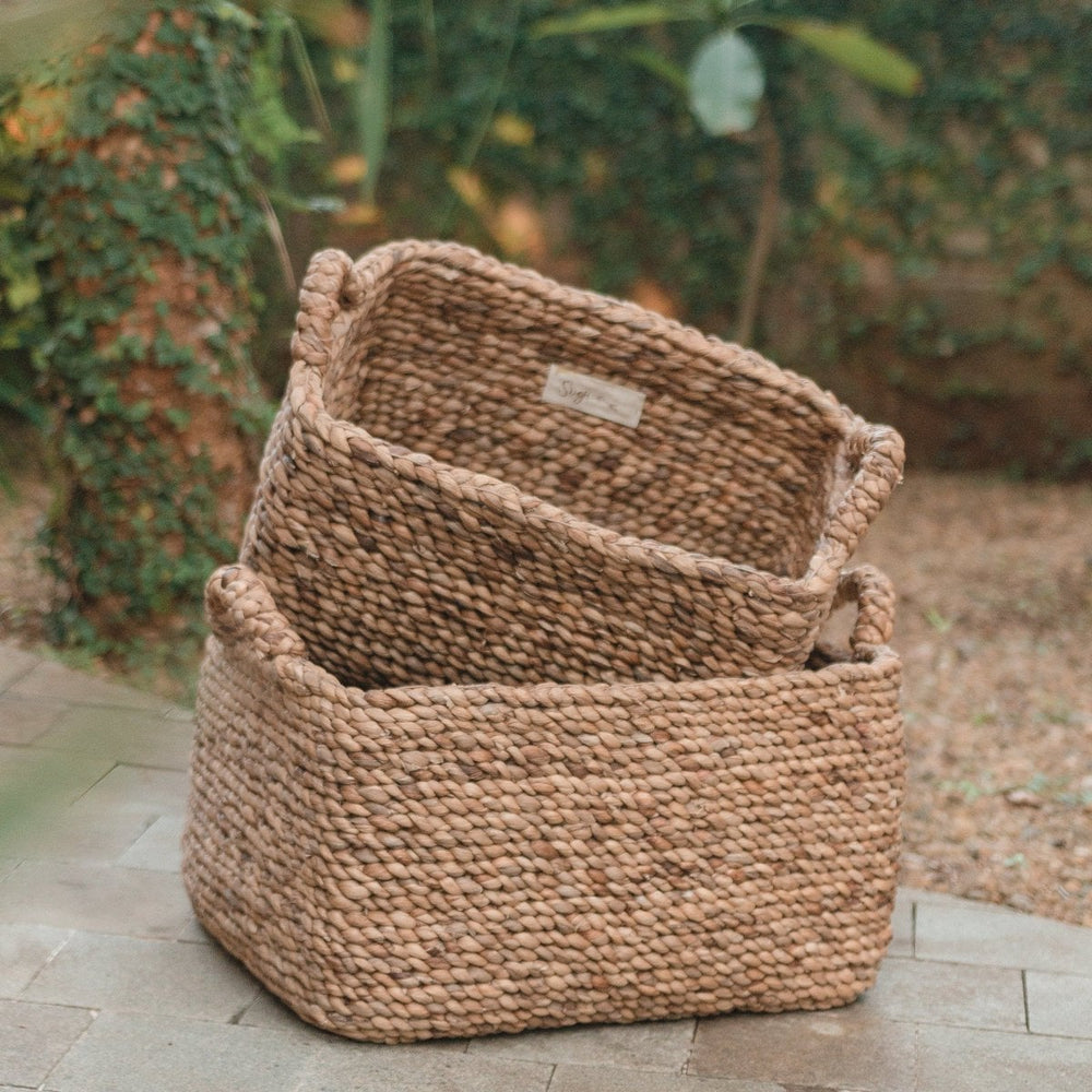 Two woven baskets on a stone surface with a blurred natural background