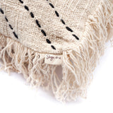Beige woven blanket with black embroidery and fringes, featuring a brand label on a white background.