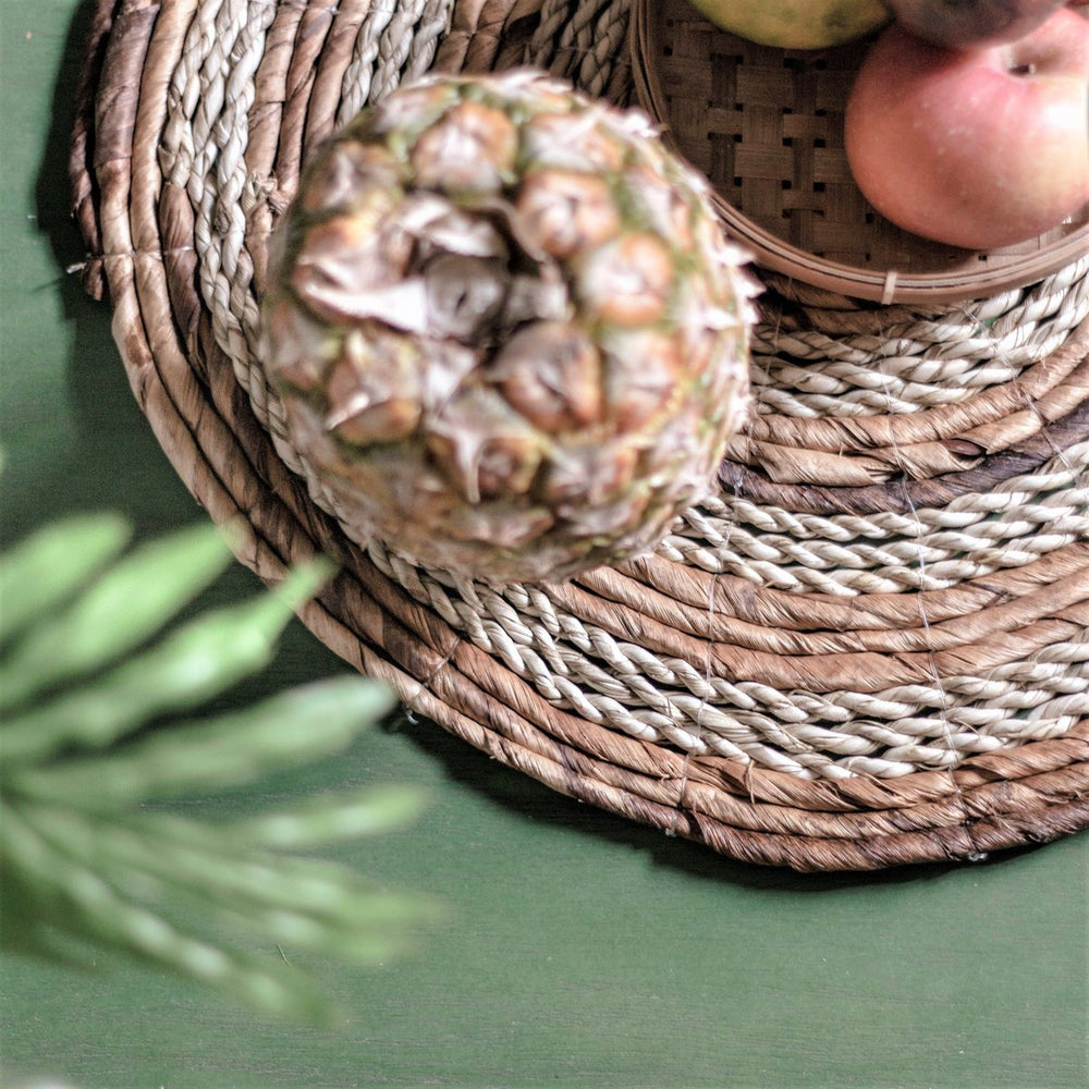 Pineapple on a woven placemat with apples in the background