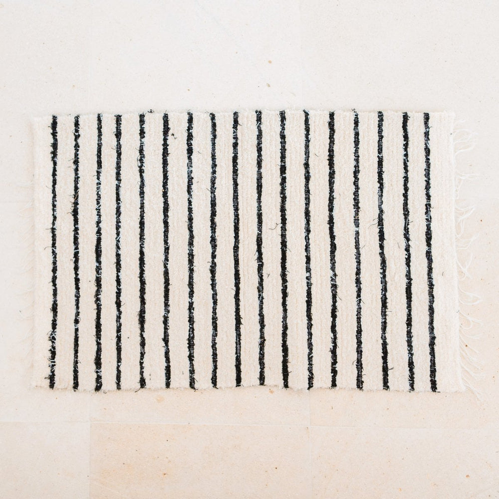 Rectangular rug with black vertical stripes on a beige background