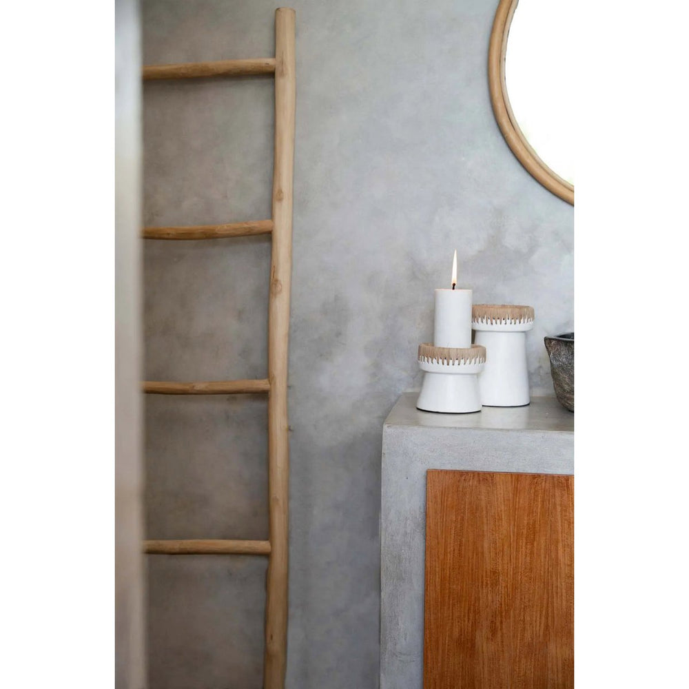 Wooden ladder against a gray wall with decorative items on a small table.