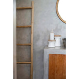 Wooden ladder against a gray wall with decorative items on a small table.