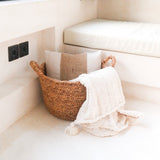 Woven basket with a white towel on a beige sofa