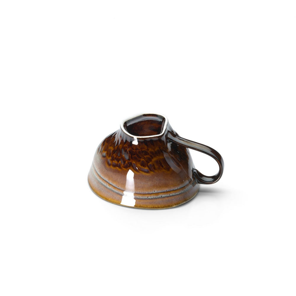 Brown ceramic cup with handle on a white background