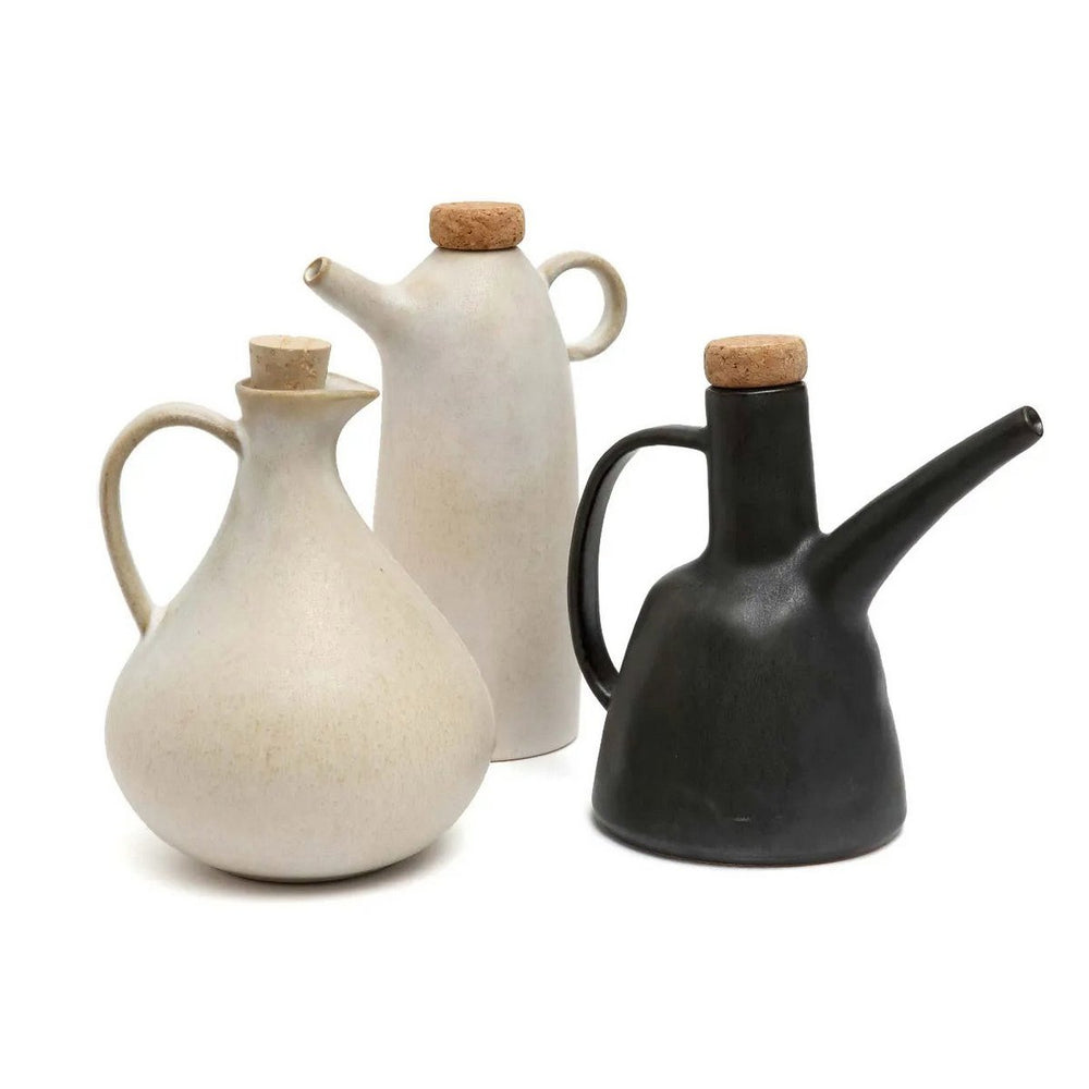 Three ceramic oil dispensers in white, beige, and black on a white background
