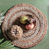 Woven placemat with a pineapple and fruits on a green surface