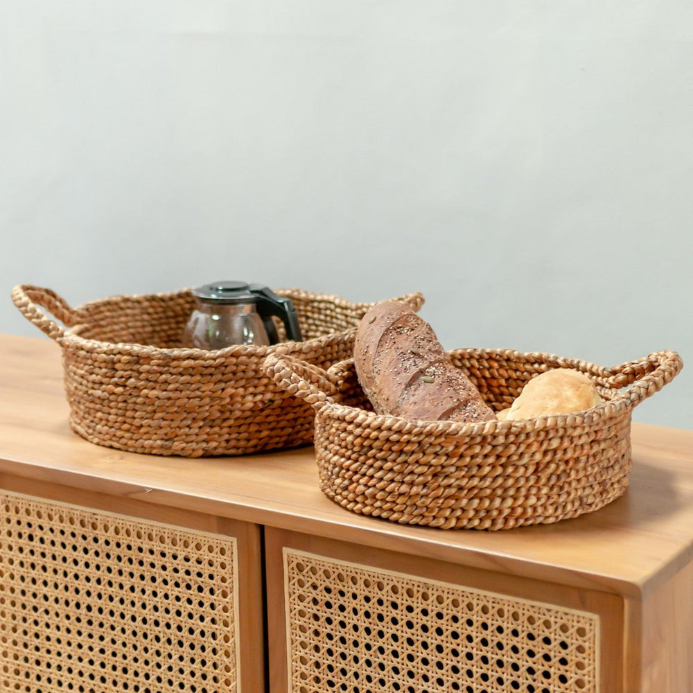 Woven baskets with bread and a teapot on a wooden surface with a light gray background