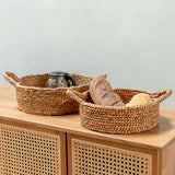 Woven baskets with bread and a teapot on a wooden surface with a light gray background