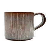 Brown ceramic mug with textured surface on a white background