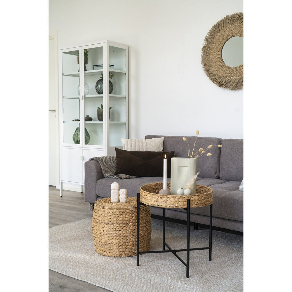 Living room with gray sofa, wicker side table, and decorative items.