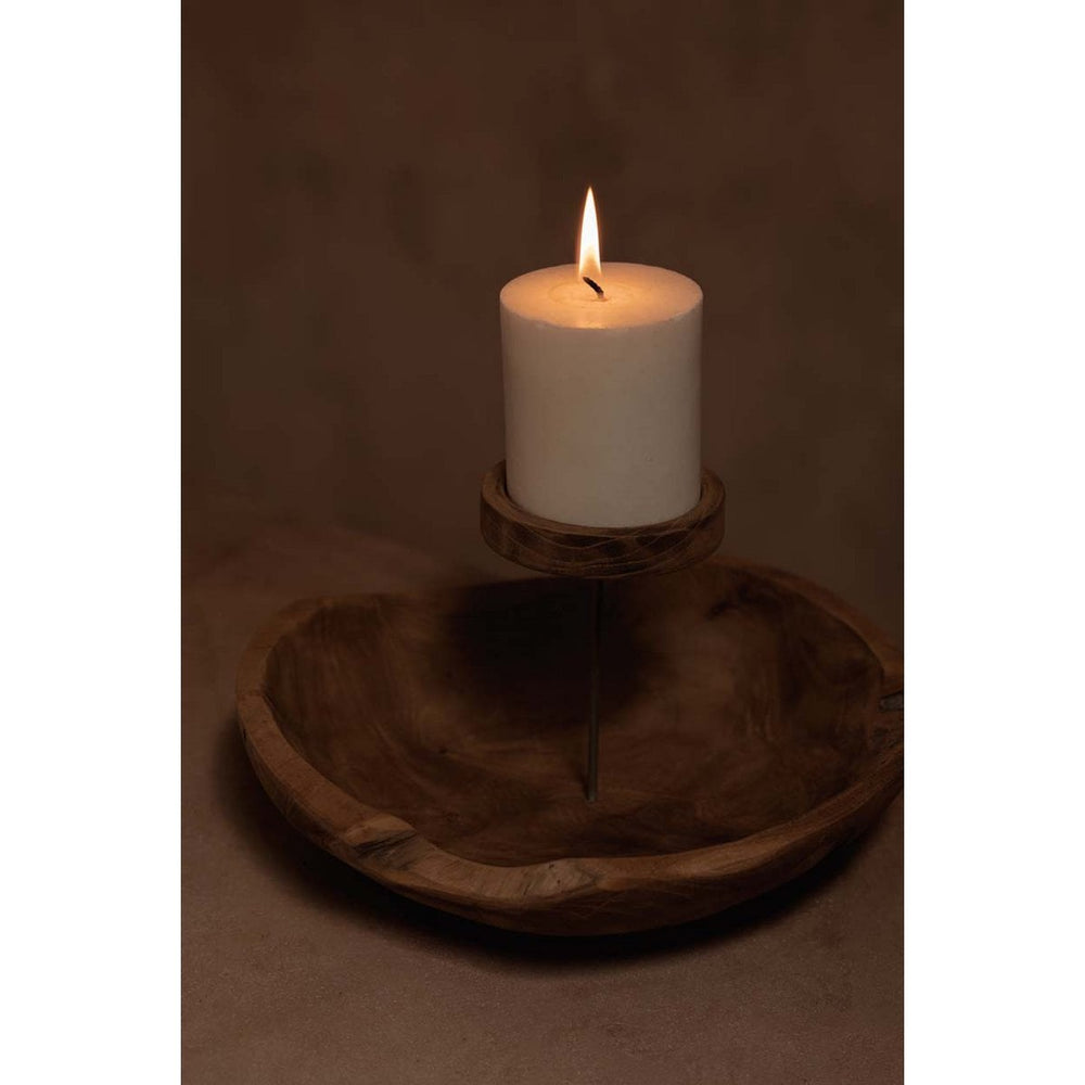 White candle on a wooden stand in a dark setting