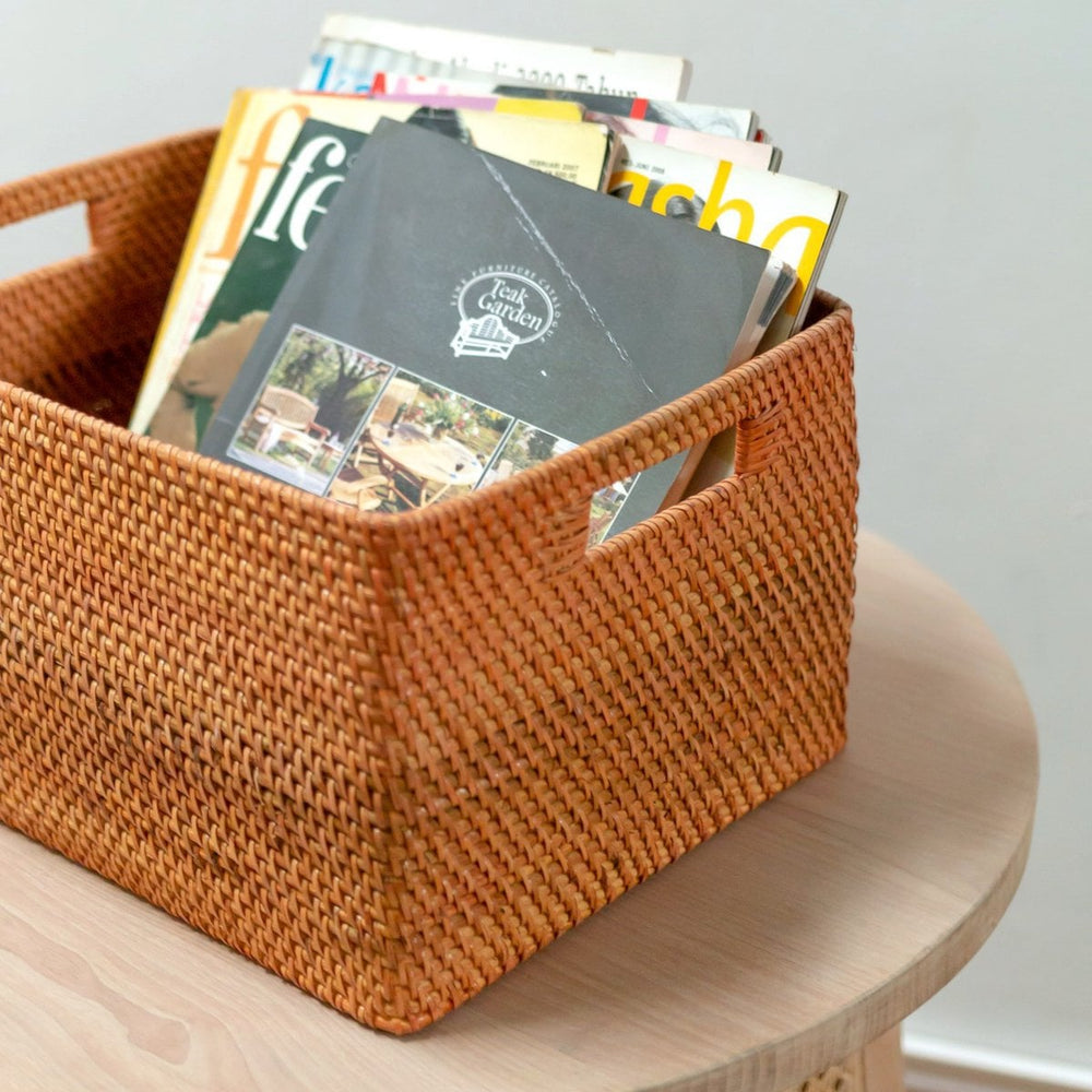 Woven basket filled with books on a wooden surface