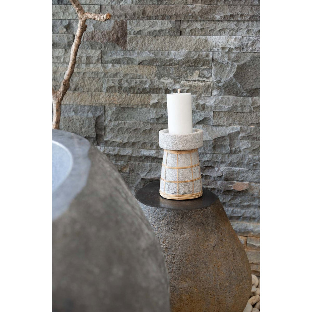 Candle in a decorative holder on a stone surface with a stone wall background