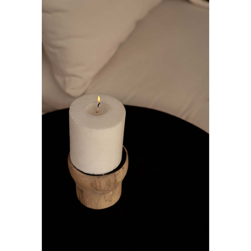 White candle on a wooden coaster with a blurred background