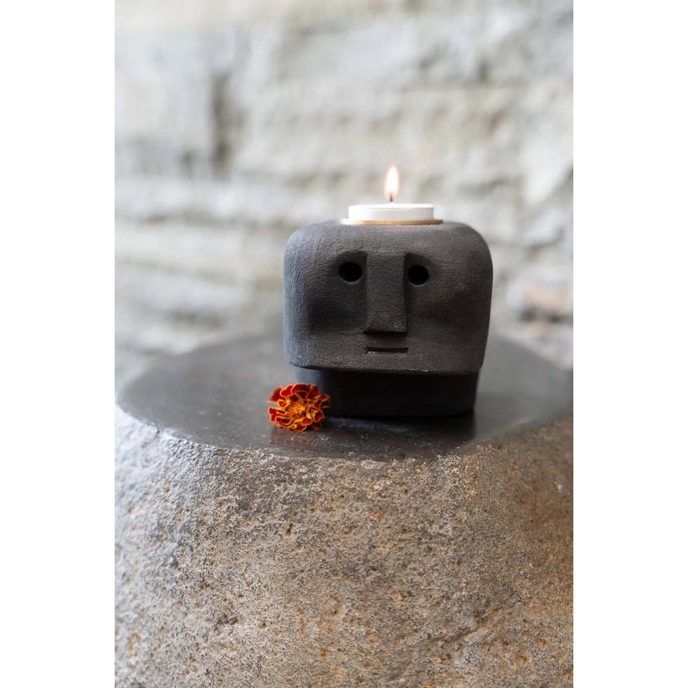 Ceramic candle holder with face design on a stone surface