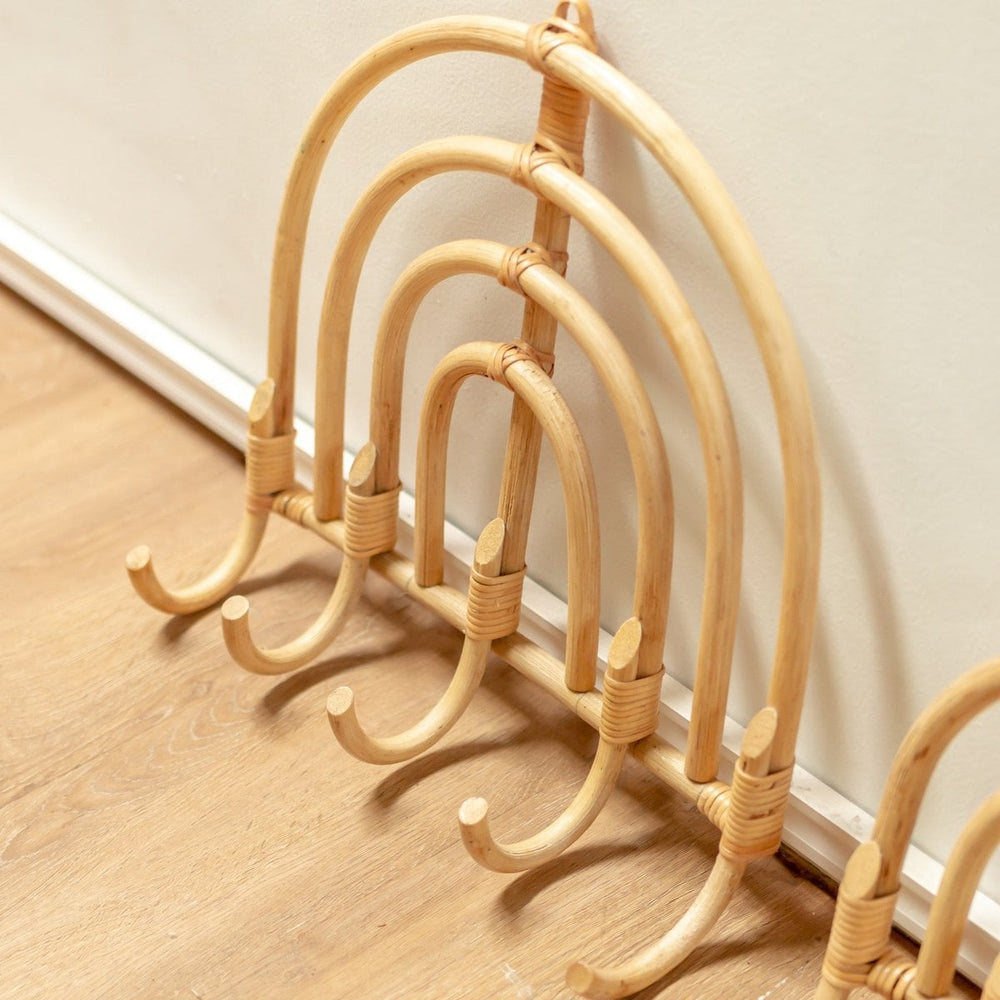 Set of wicker coat hangers on a wooden floor against a white wall.