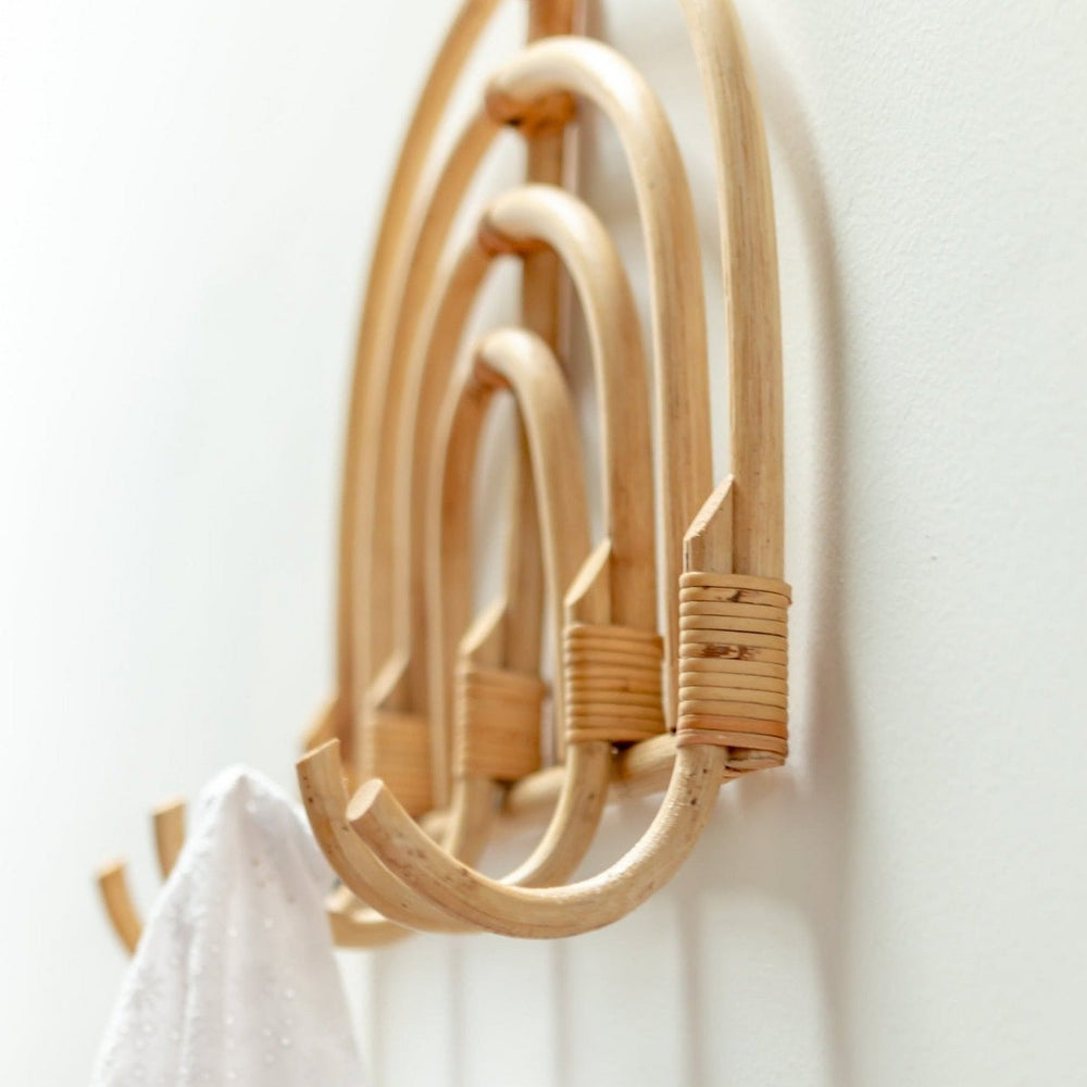 Wooden coat rack with hooks on a white wall