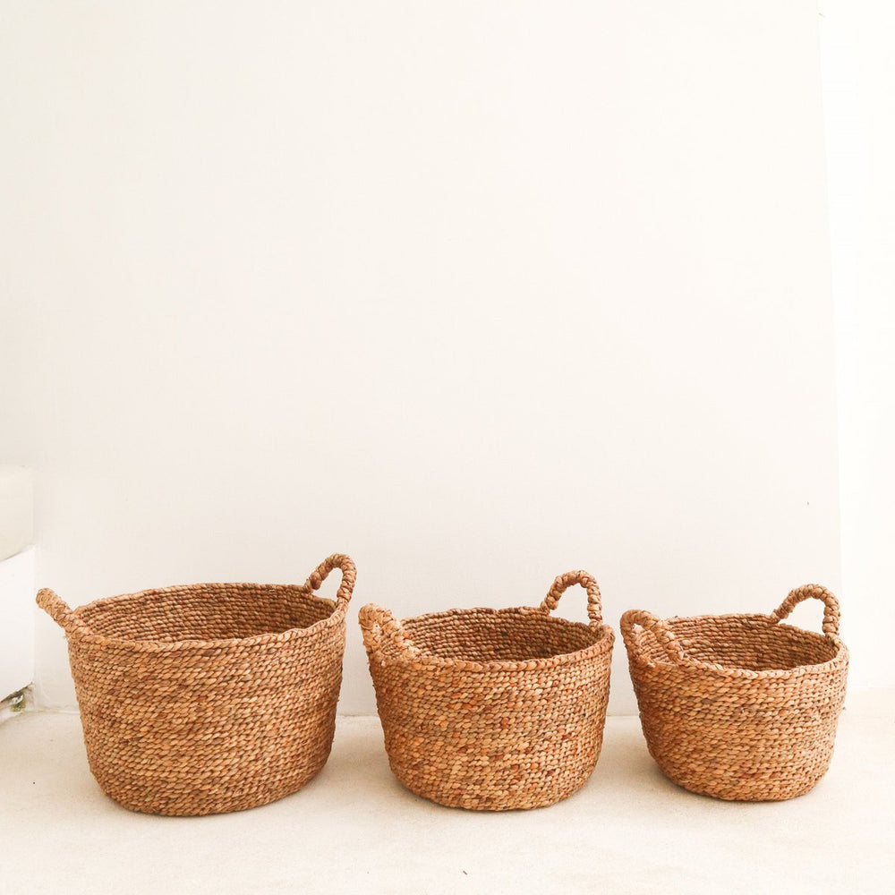 Three woven baskets of different sizes on a light background