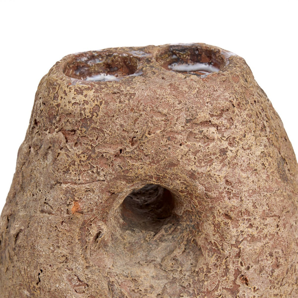 Close-up of a textured brown ceramic object with a central hole on a white background