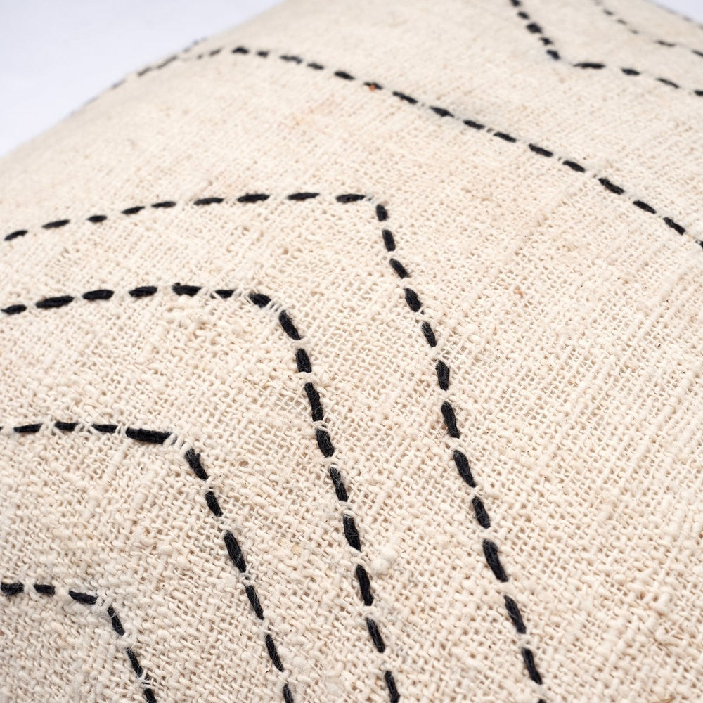 Close-up of a beige fabric with black stitching patterns on a white background