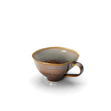 Ceramic cup with brown and gray glaze on a white background