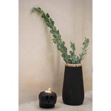 Black vase with greenery and black candle on a neutral background
