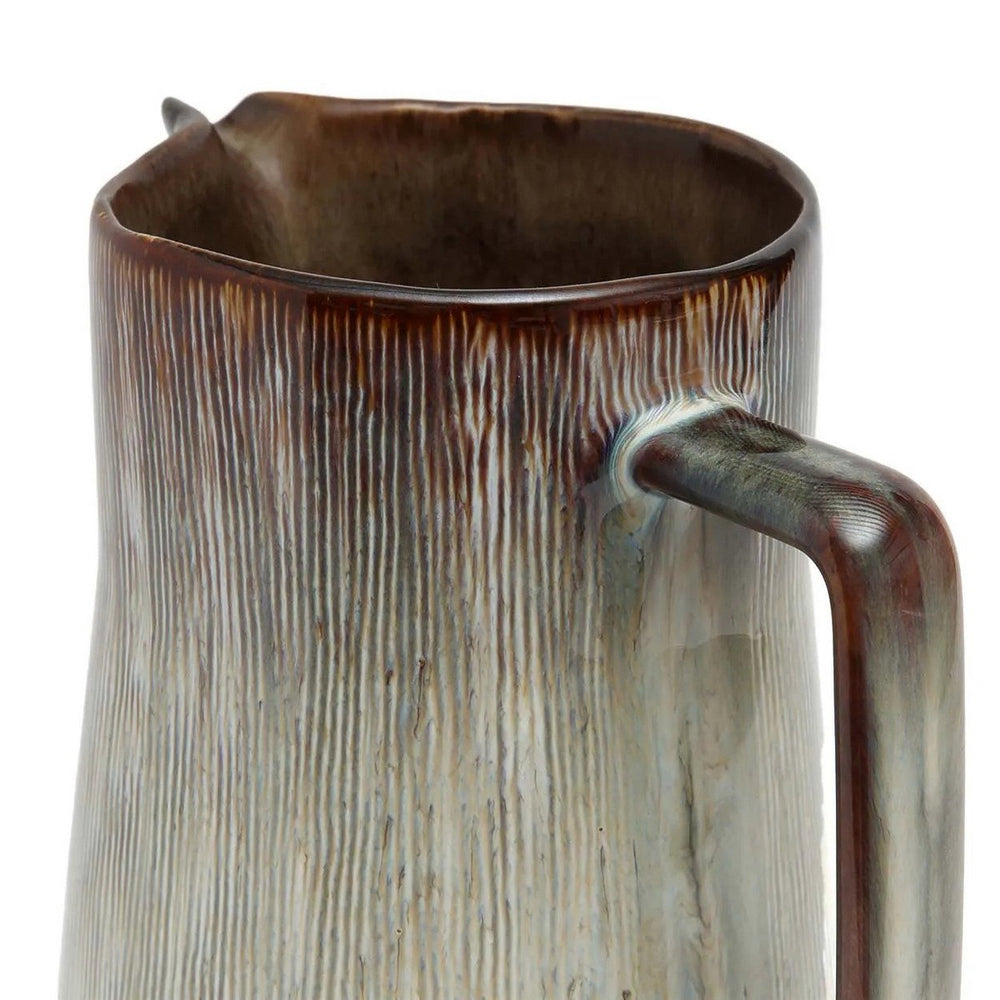 Ceramic pitcher with textured surface and handle on a white background