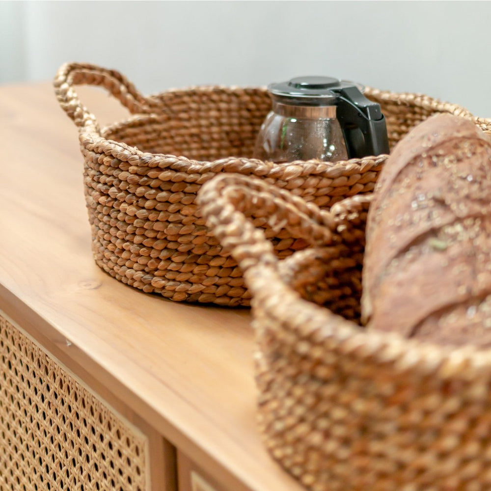 Woven baskets on a wooden surface with a glass jar and bread loaf.