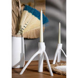 White candle holders with candles on a wooden surface, with decorative elements in the background.